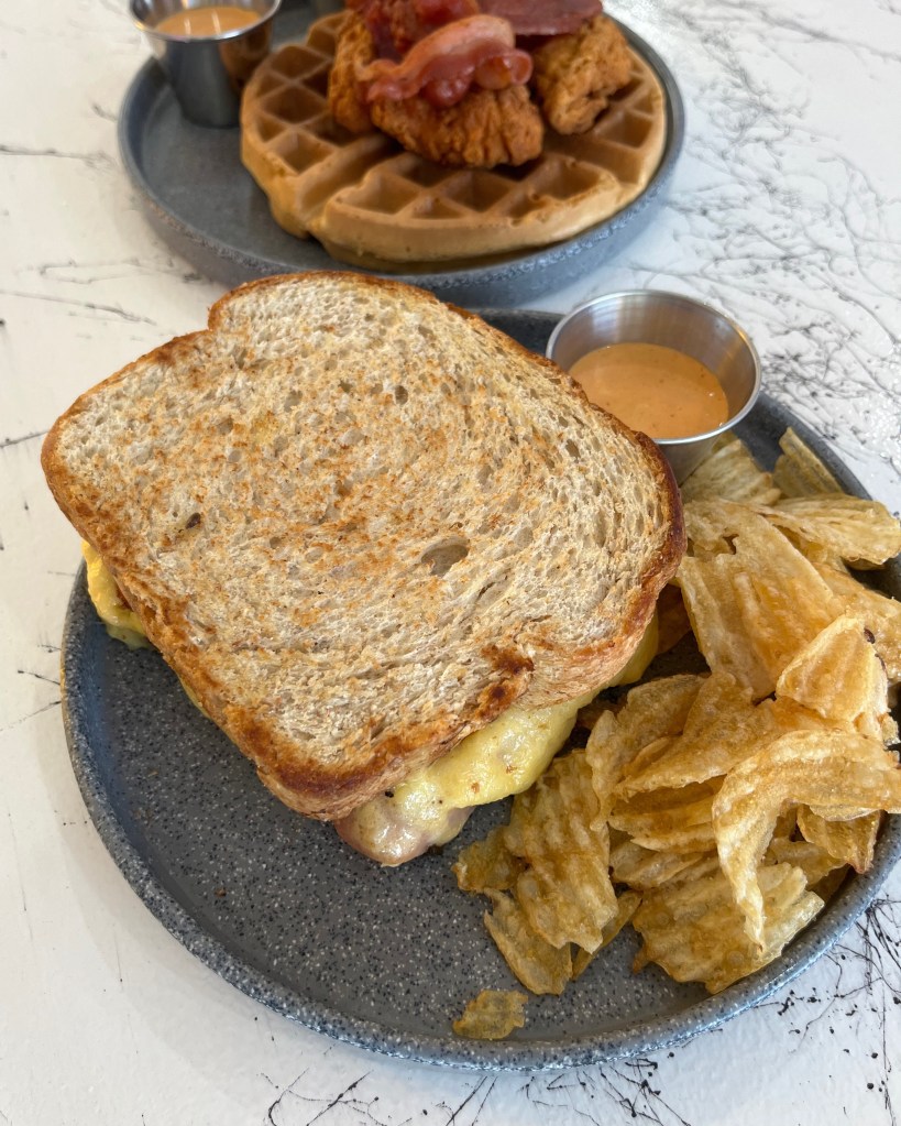 Sándwich de queso, tocino y huevo. Chips papas fritas.